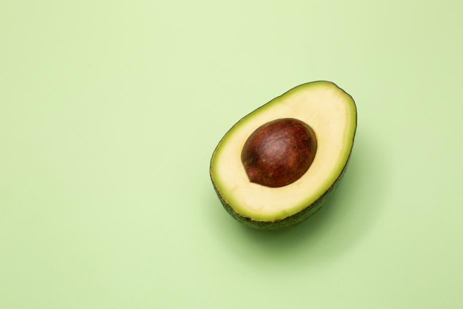 An avocado cut in half on a green background