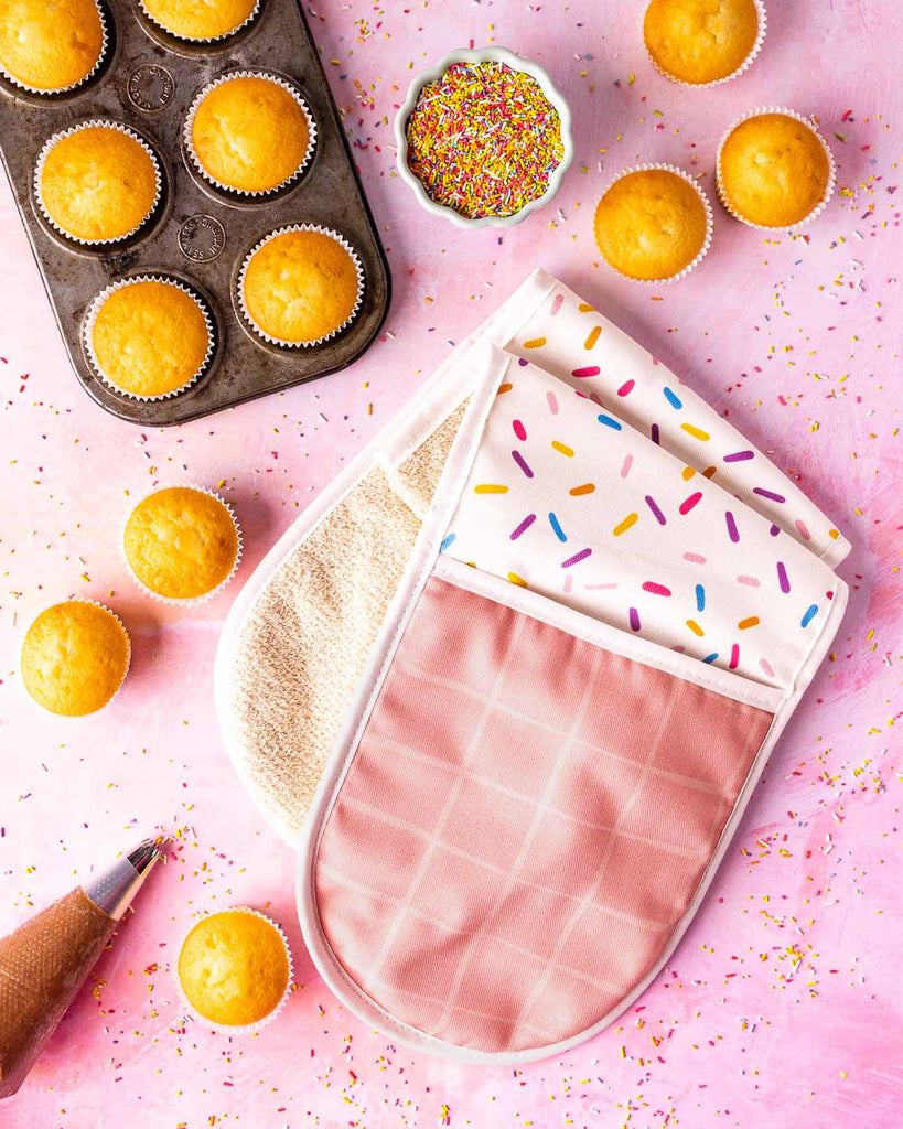 Whitworths Sprinkle Oven glove laid next cupcakes