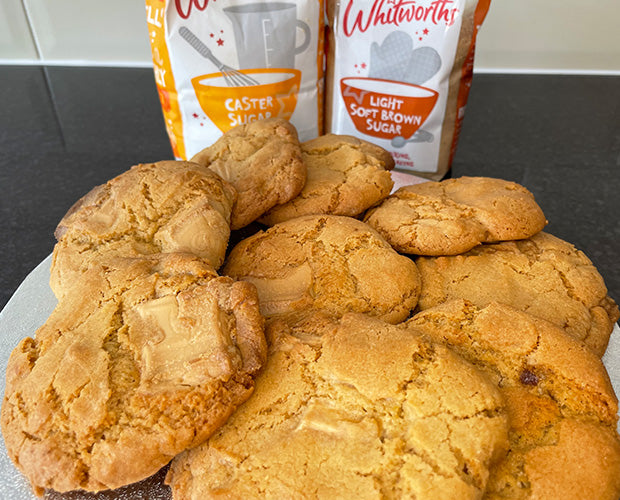 A selection of cookies on a silver tray, with Whitworths Caster and Whitworths Light Soft Brown sugars in the background.