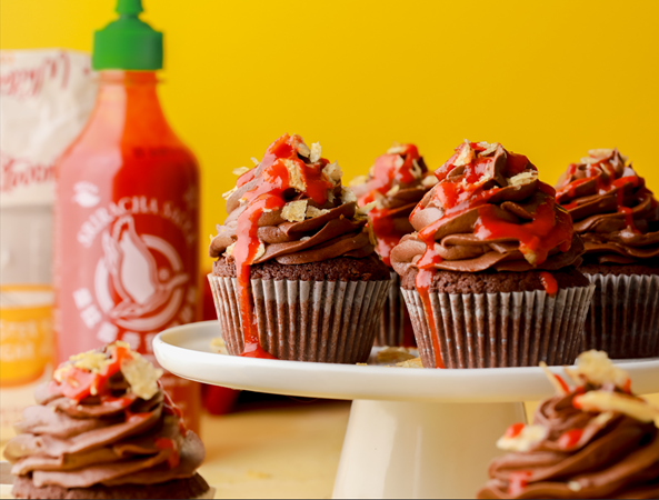 Chilli Chocolate and Salty Sriracha Cupcakes topped with a chili-infused chocolate buttercream, sprinkled with crunchy Kettle Chips, and generously drizzled with Sriracha chili sauce