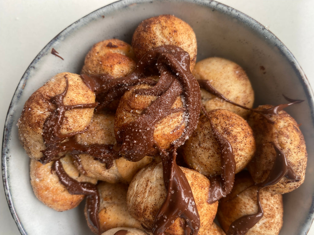 mini doughnut balls covered in melted chocolate and cinnamon sugar