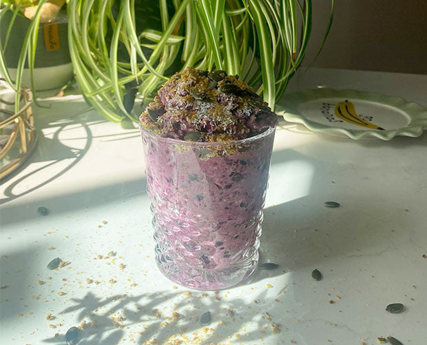 A glass filled with overnight oats and chia seeds, made and topped with fresh blueberries
