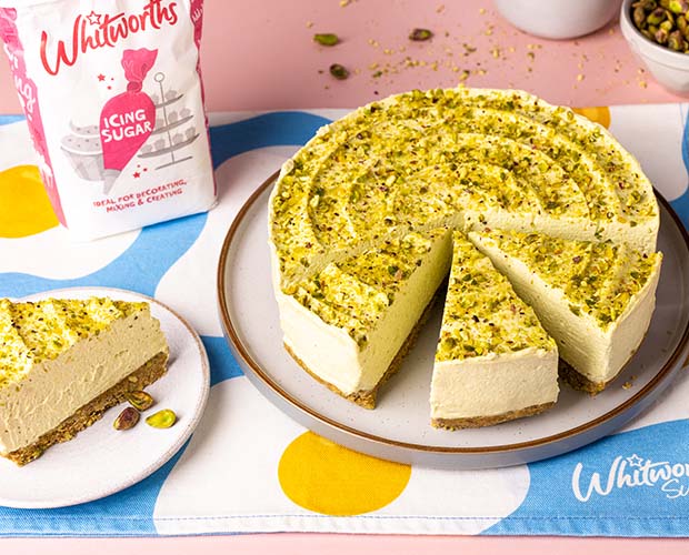 Pistachio cheesecake sliced up and topped with pistachio crumbs