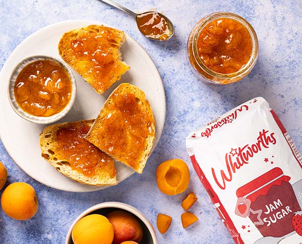 Apricot jam spread on toast and photographed next to a Whitworths Jam Sugar bag