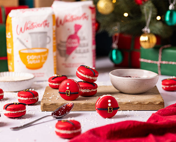 These festive red macarons are decorated to look like Santa’s suit, complete with black belts and golden buckles with royal icing. Set against a Christmas backdrop with Whitworths sugar bags, gifts, and Christmas ornaments.