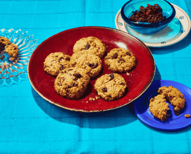 A pile of oat and sultana cookies on a colourful plate