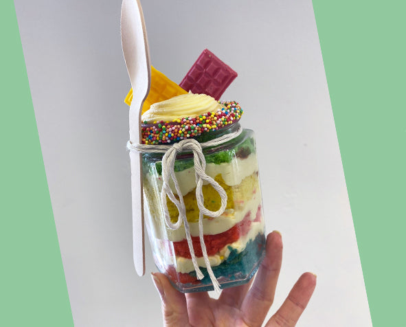 a colourful cake in a jar topped with buttercream