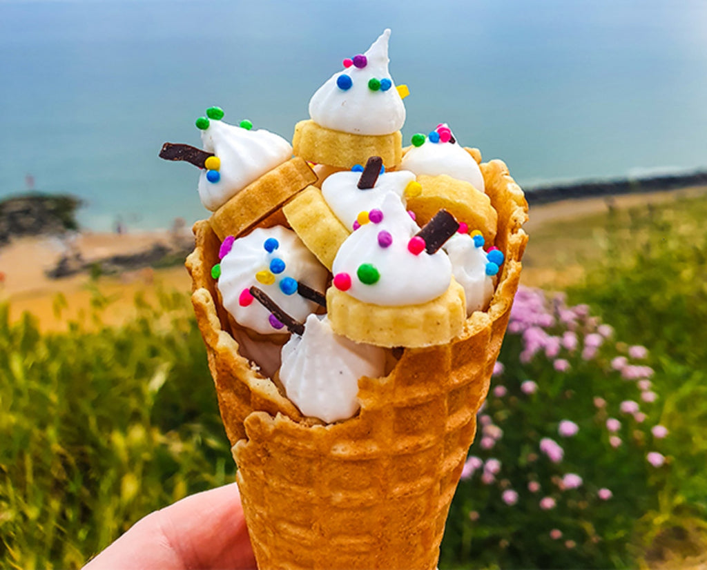 A pile of iced gems topped with colourful sprinkles in an ice cream cone